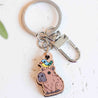 Charming wooden keyring of a capybara with a small bird perched on its head, finely engraved with natural details. hand-painted, eco gift, sustainable gift
