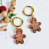 Wooden gingerbread man keychains on a textured surface with decorative elements.