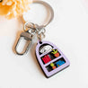 Hand-painted wooden keyring featuring a sleeping cat on stacked books