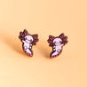 A pair of pink axolotl stud earrings made of wood, displayed on a light background.