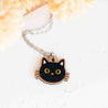 Black cat-shaped pendant on a chain against a light background