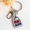 Hand-painted wooden keyring featuring a sleeping cat on stacked books