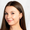 Close-up of a woman wearing pink axolotl earrings against a white background