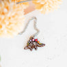 Necklace with a colorful dinosaur pendant on a textured white surface.