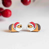 Two small figurines of guinea pigs wearing Santa hats on a light background.
