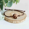 Bracelet with a wooden yin yang symbol on a wooden disc with a plant in the background