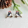 Bird-shaped earrings with red hats on a snowy background