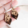 Wooden howling wolf drop earrings with mountain and crescent moon details.