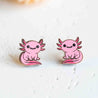 Pink axolotl-shaped earrings on a light background