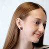 Close-up of a person wearing a black cat earring on a white background